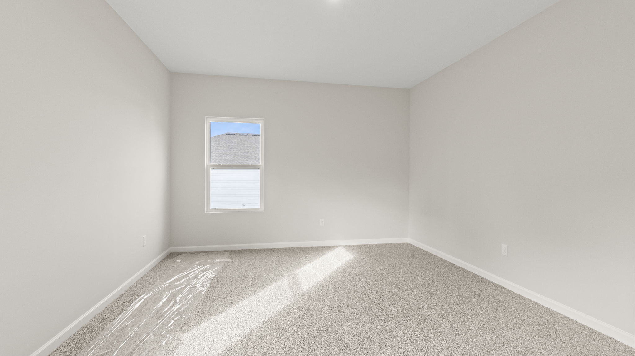 Carpeted primary bedroom with windoe and three outlets