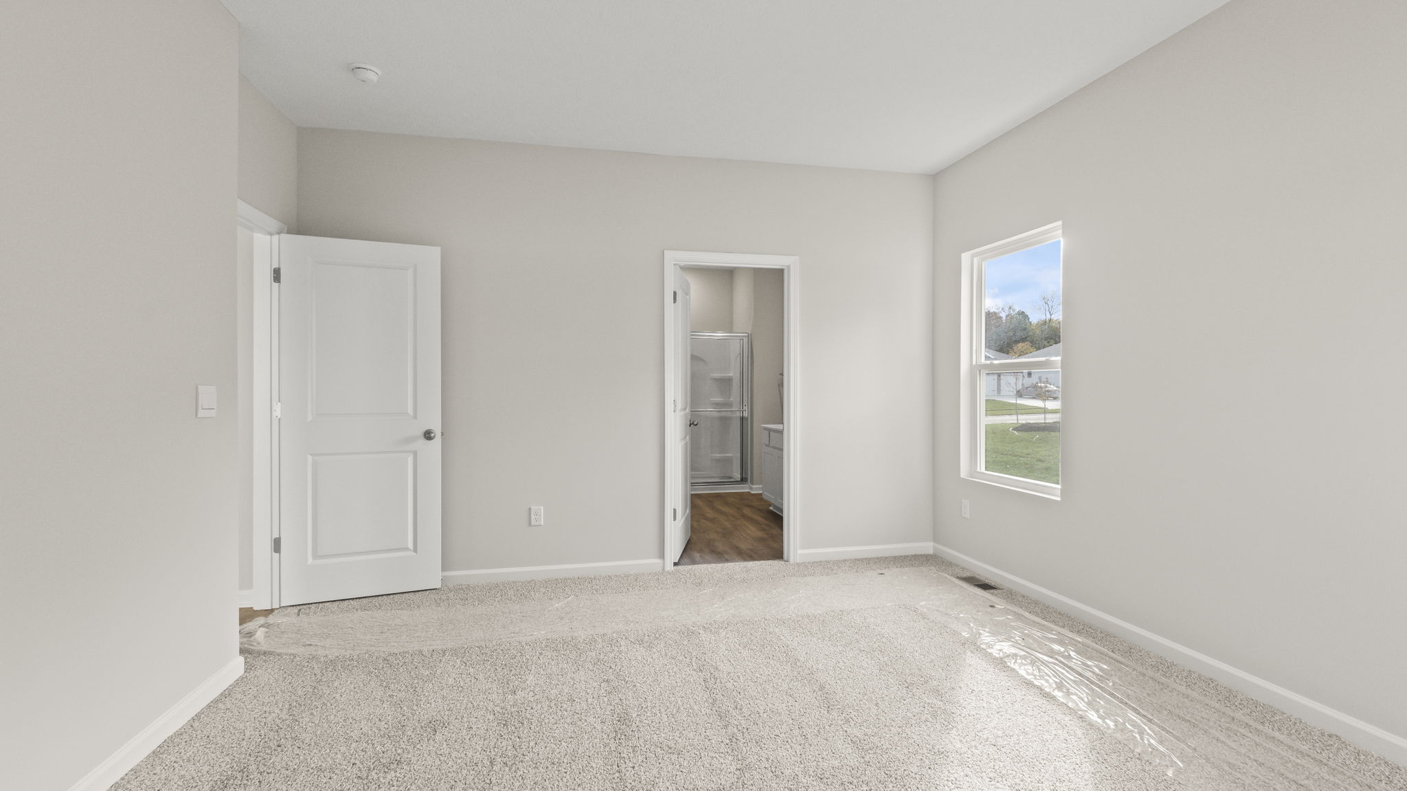 Primary bedroom looking into primary bathroom with walk-in shower in frame.