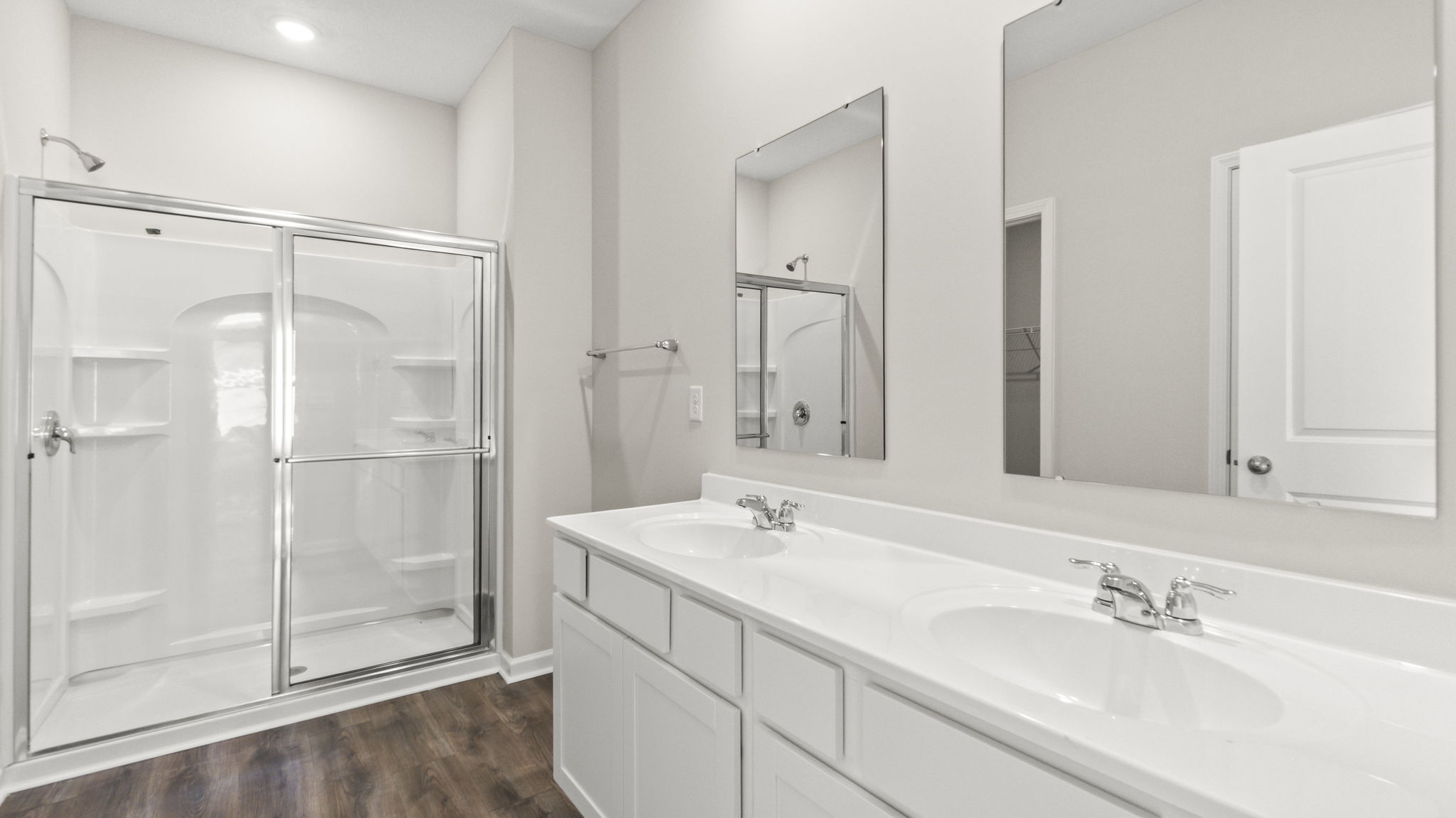 Double-sink vanity with dual-mirror and walk-in shower with tiered shelving