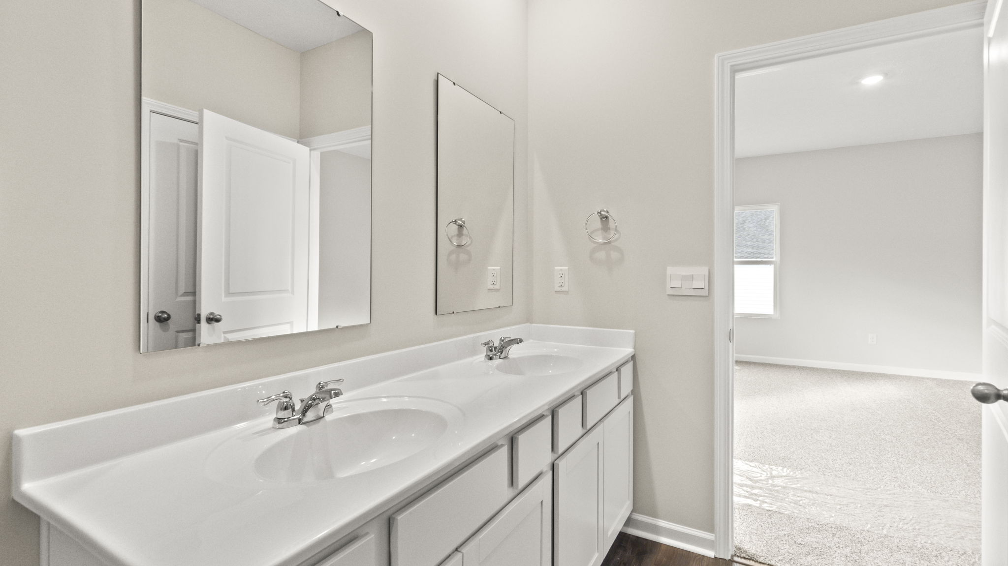 Double sink vanity with view of primary bathroom