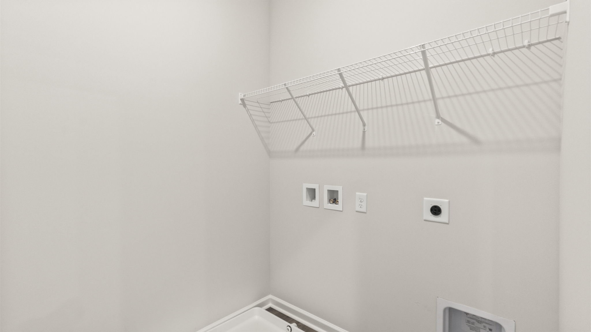 Laundry area with wire shelving and washer/dryer inlets.