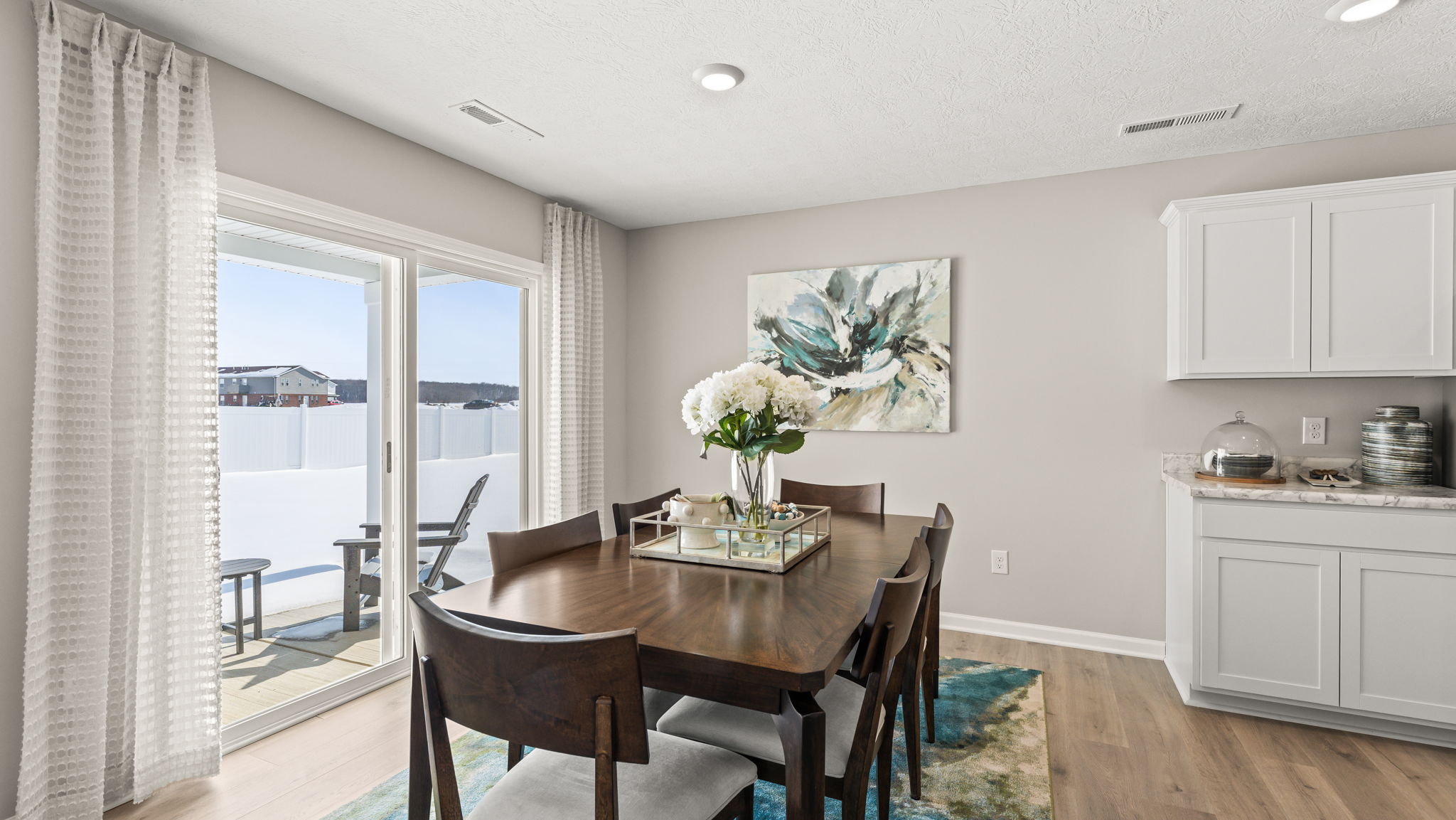 Three-quarter perspective of modern dining room with wooden table and white/green natural centerpiece