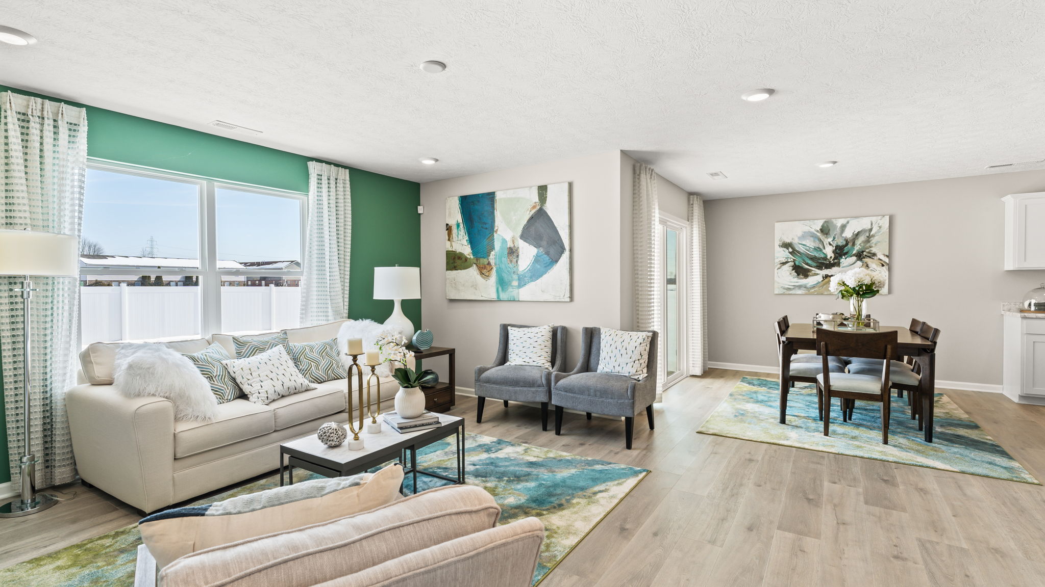 Great room with couches, dining room table, and windows open with abundant natural light