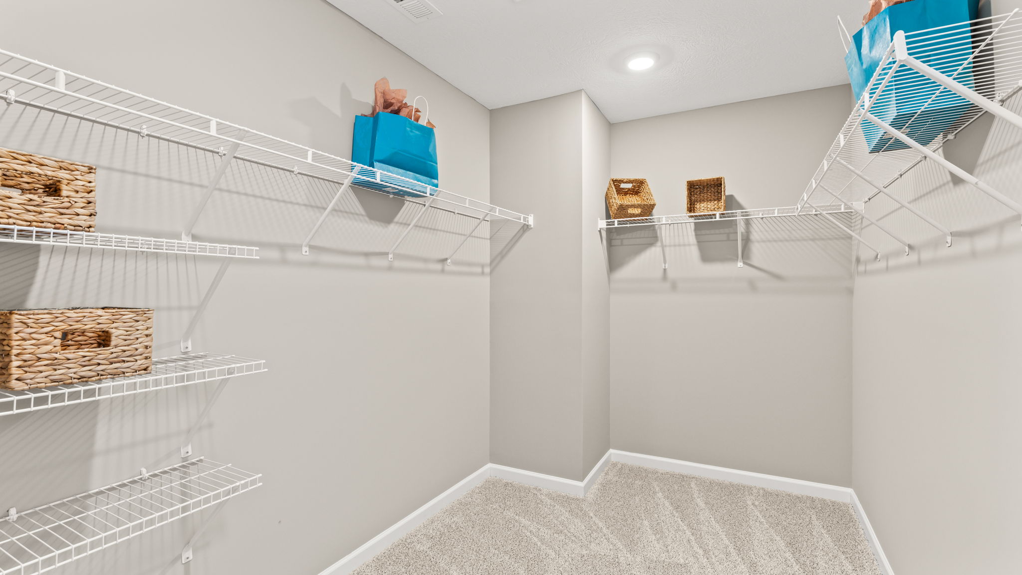 Walk-in closet decorated with blue and brown storage boxes on wire rack shelving