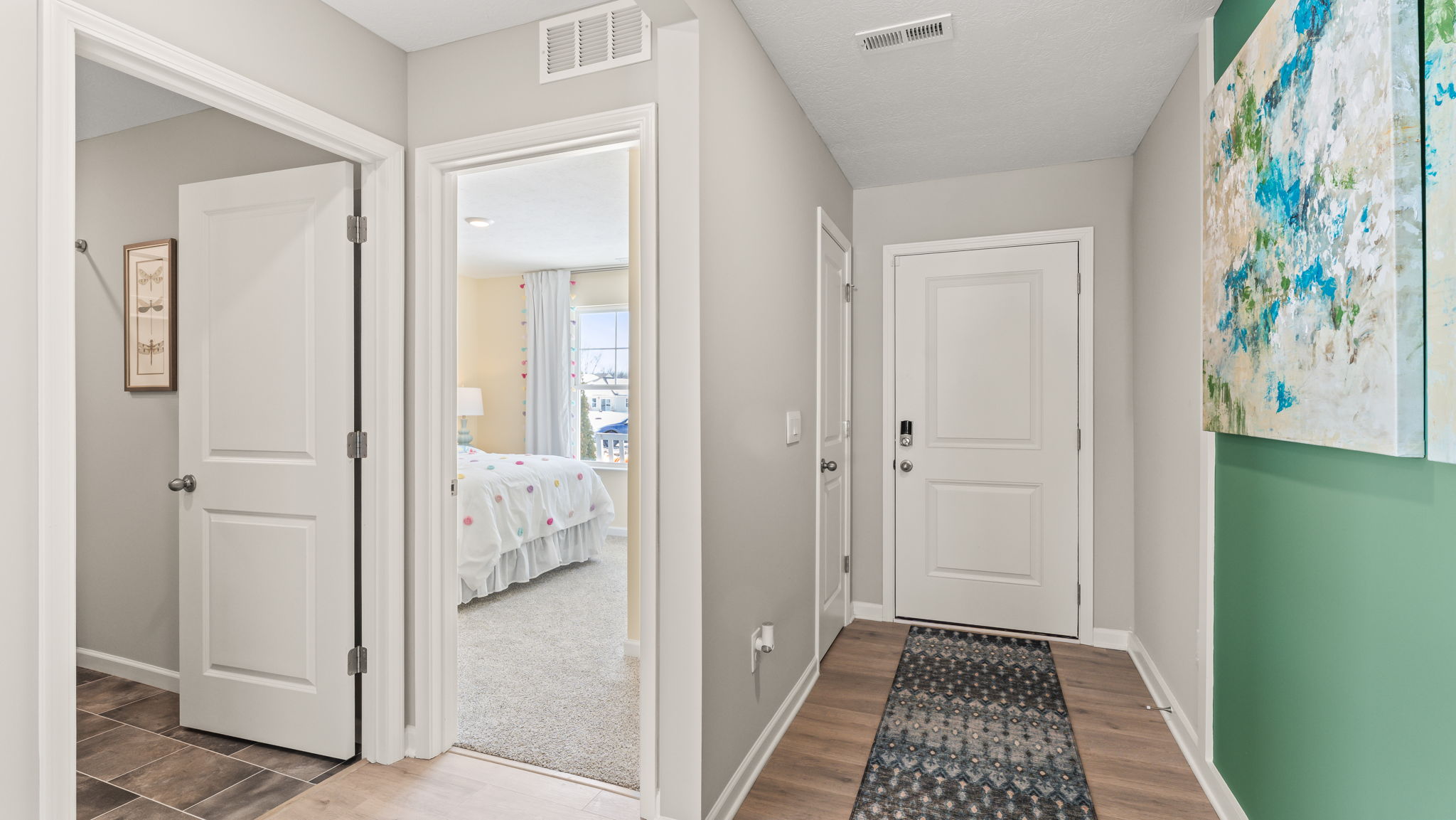 Hallway at the front of the home with doors leading to bathroom, bedroom, and exterior of home