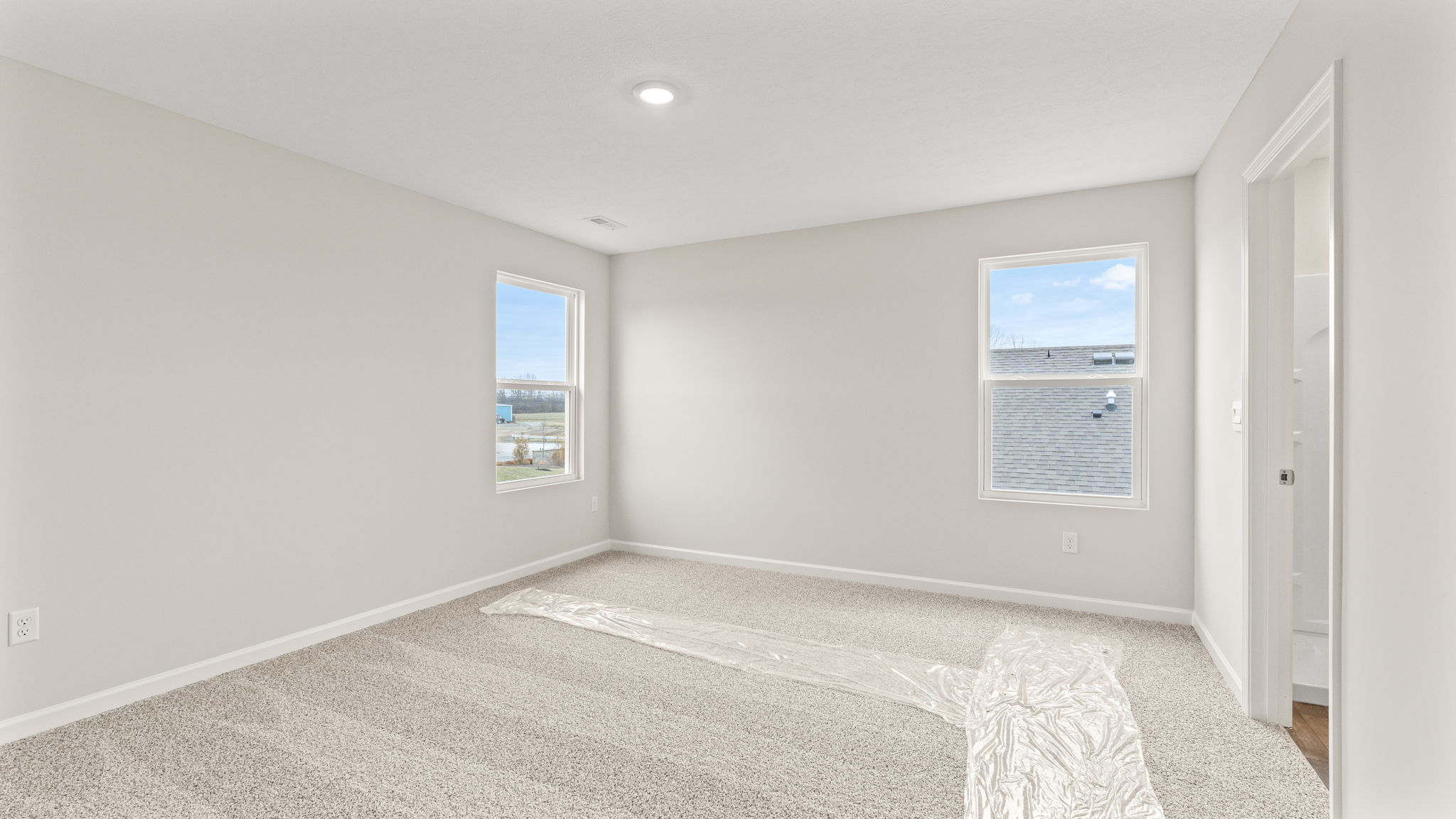Primary bedroom with two windows and carpet