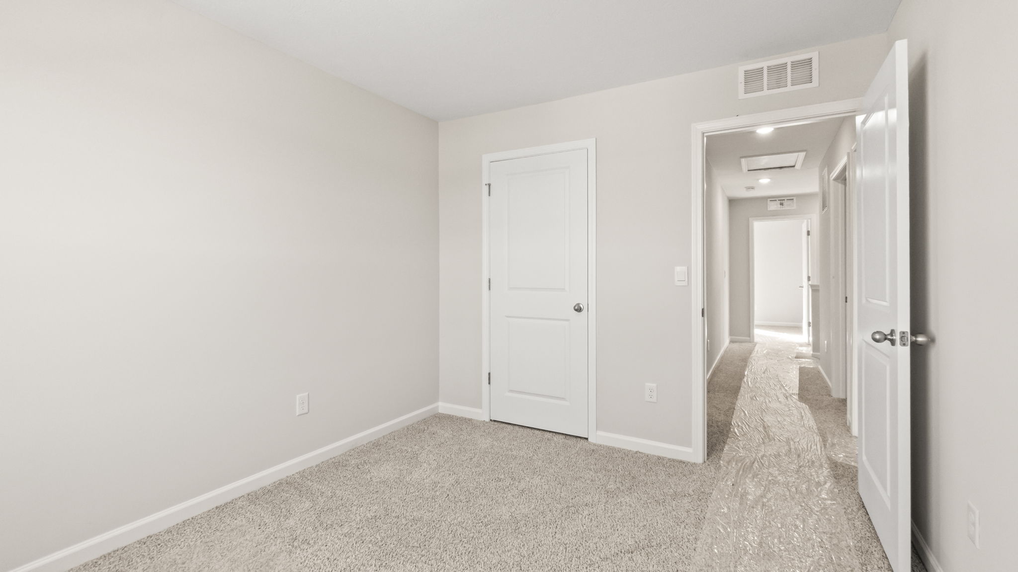 Carpeted bedroom with view of closet and hallway doors