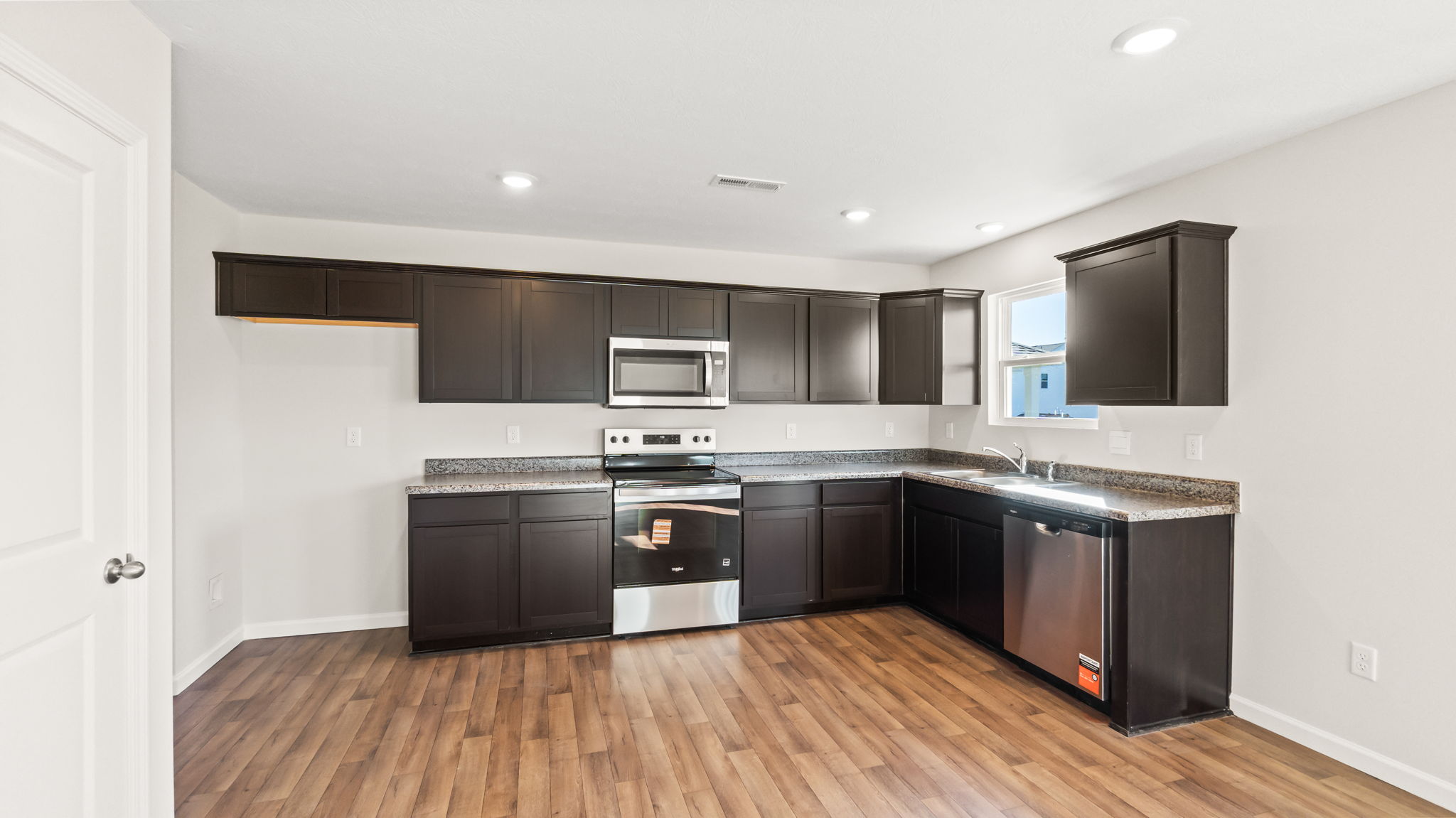 wide angle image of kitchen with woodlook flooring and wood cabinetry