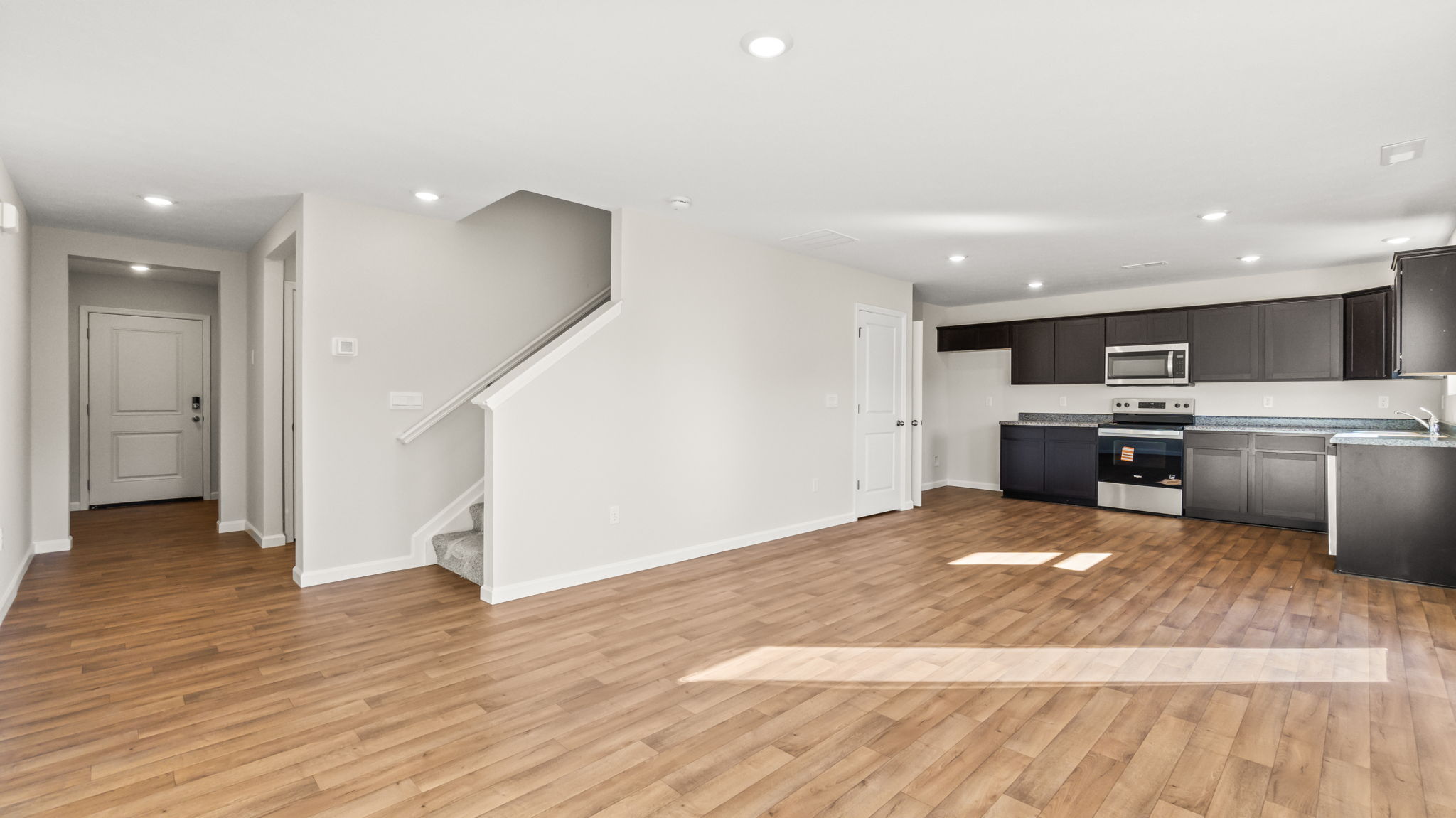 Wide image of kitchen adjacent to stairs to second level
