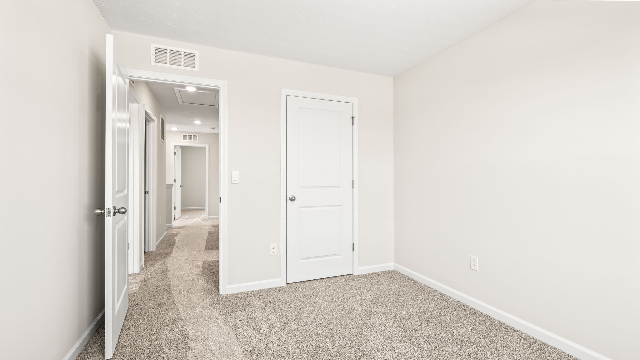 Carpeted bedroom with doors to hallway and closet