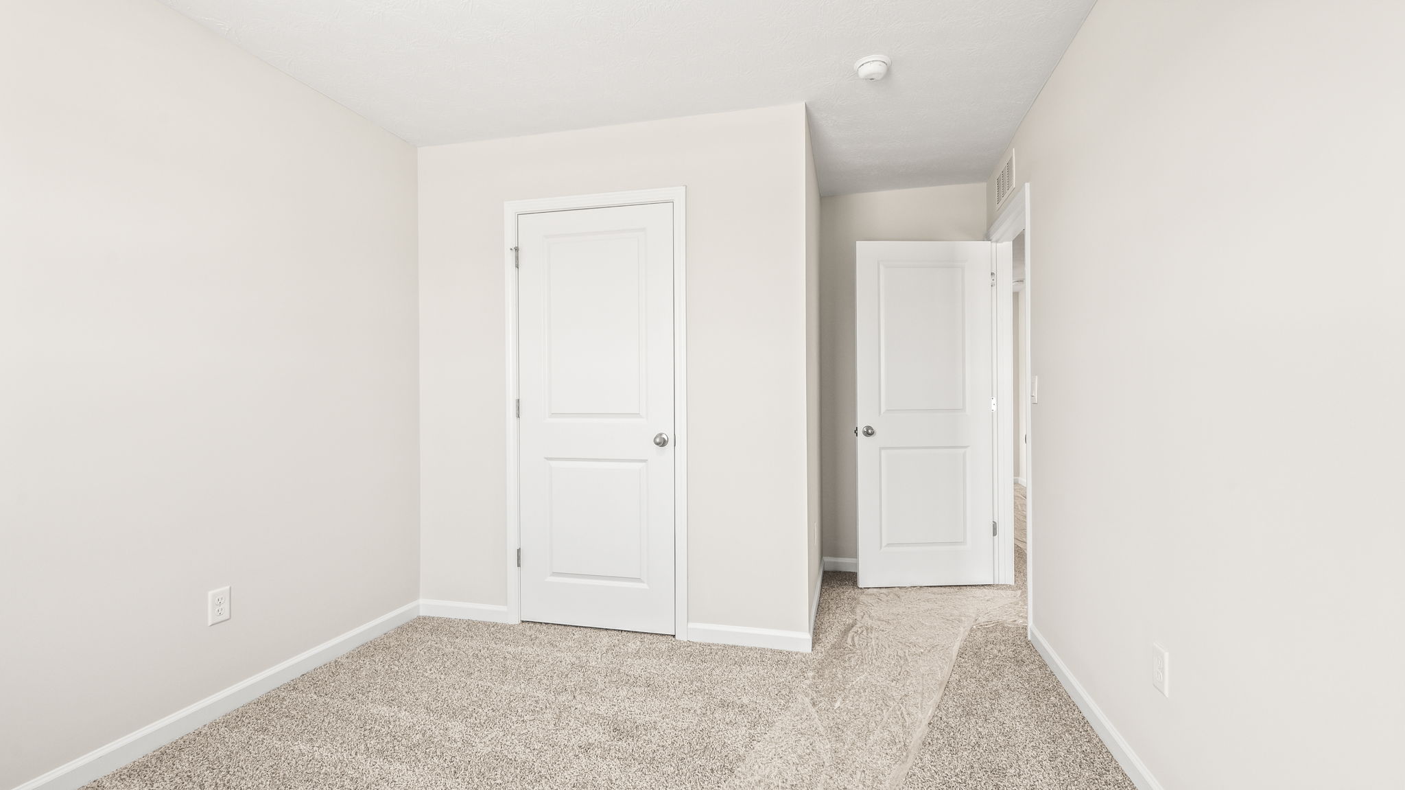 Carpeted bedroom with doors to hallway and closet