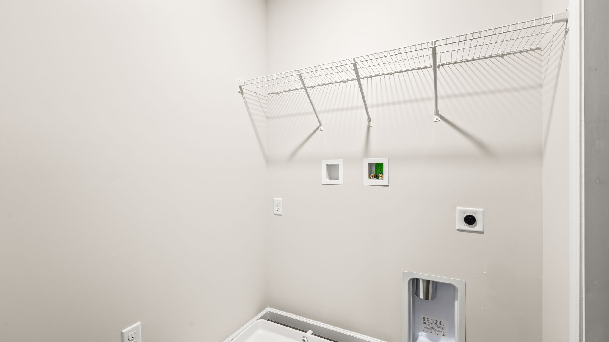 Laundry Area with wire rack shelving and washer/dryer inlets