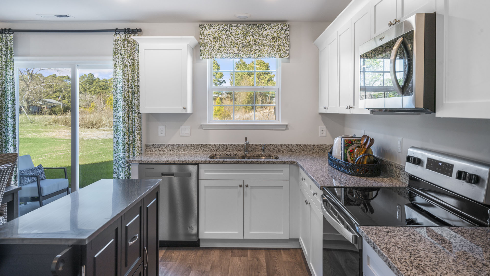 kitchen area with large window into backyard and quartz countertops.