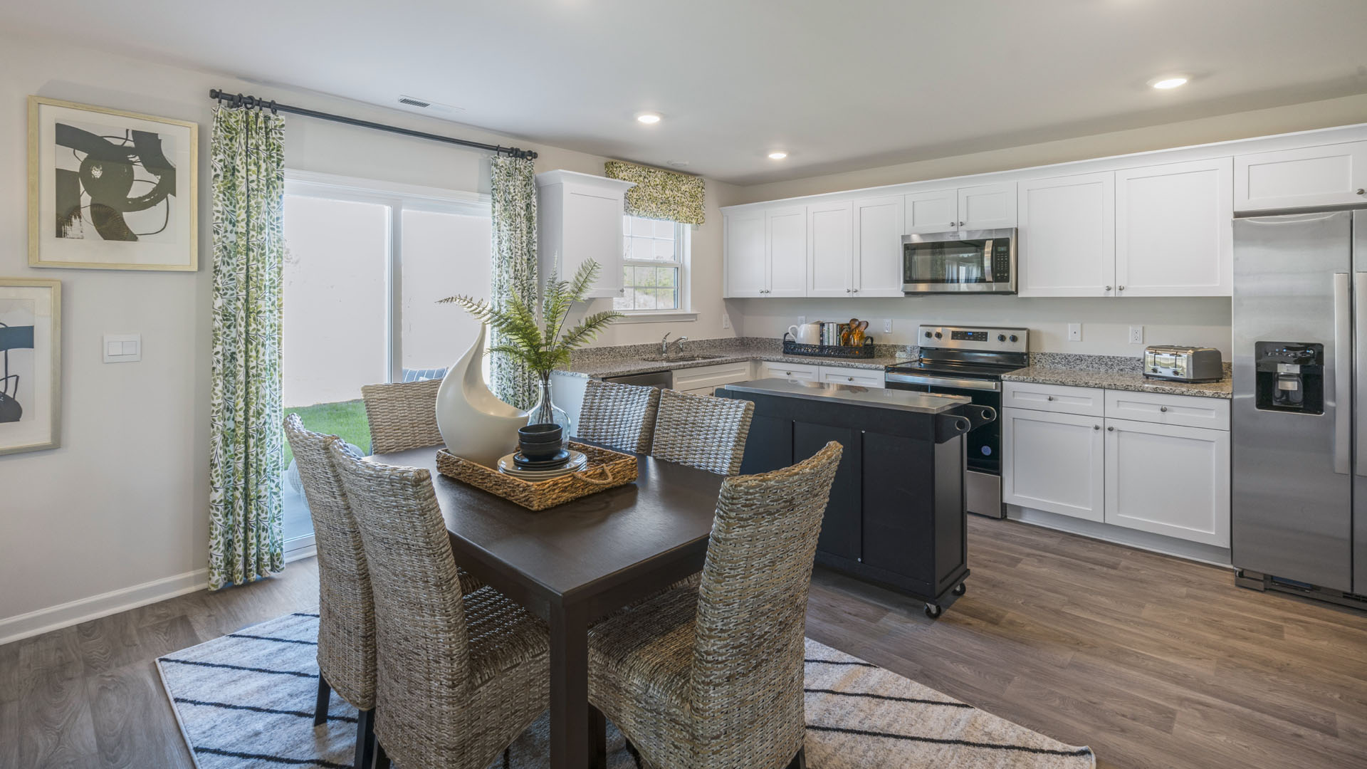Modern open concenpt dining room and kitchen area with white cabinets and stainless steel appliances.