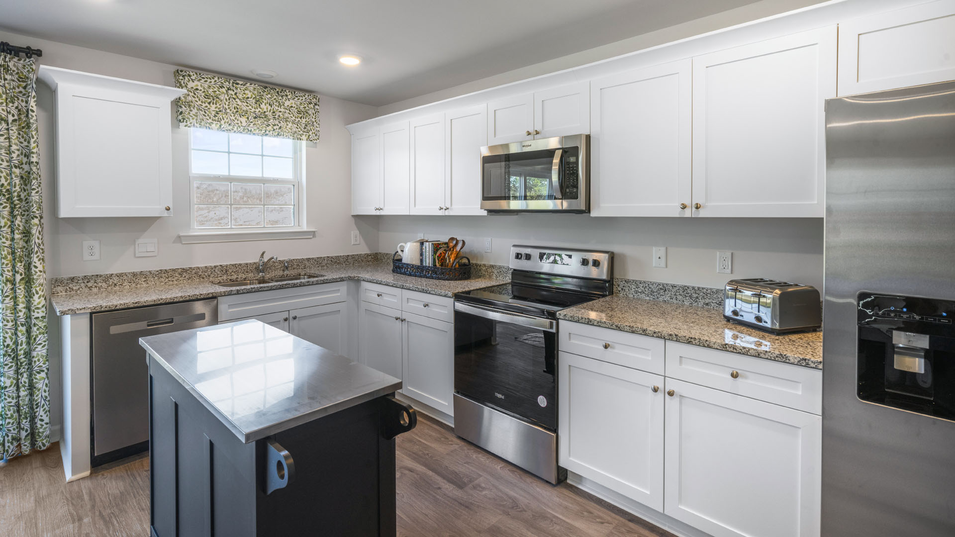kitchen island with stainless steel top adjacent to whirlpool stainless steel appliances.