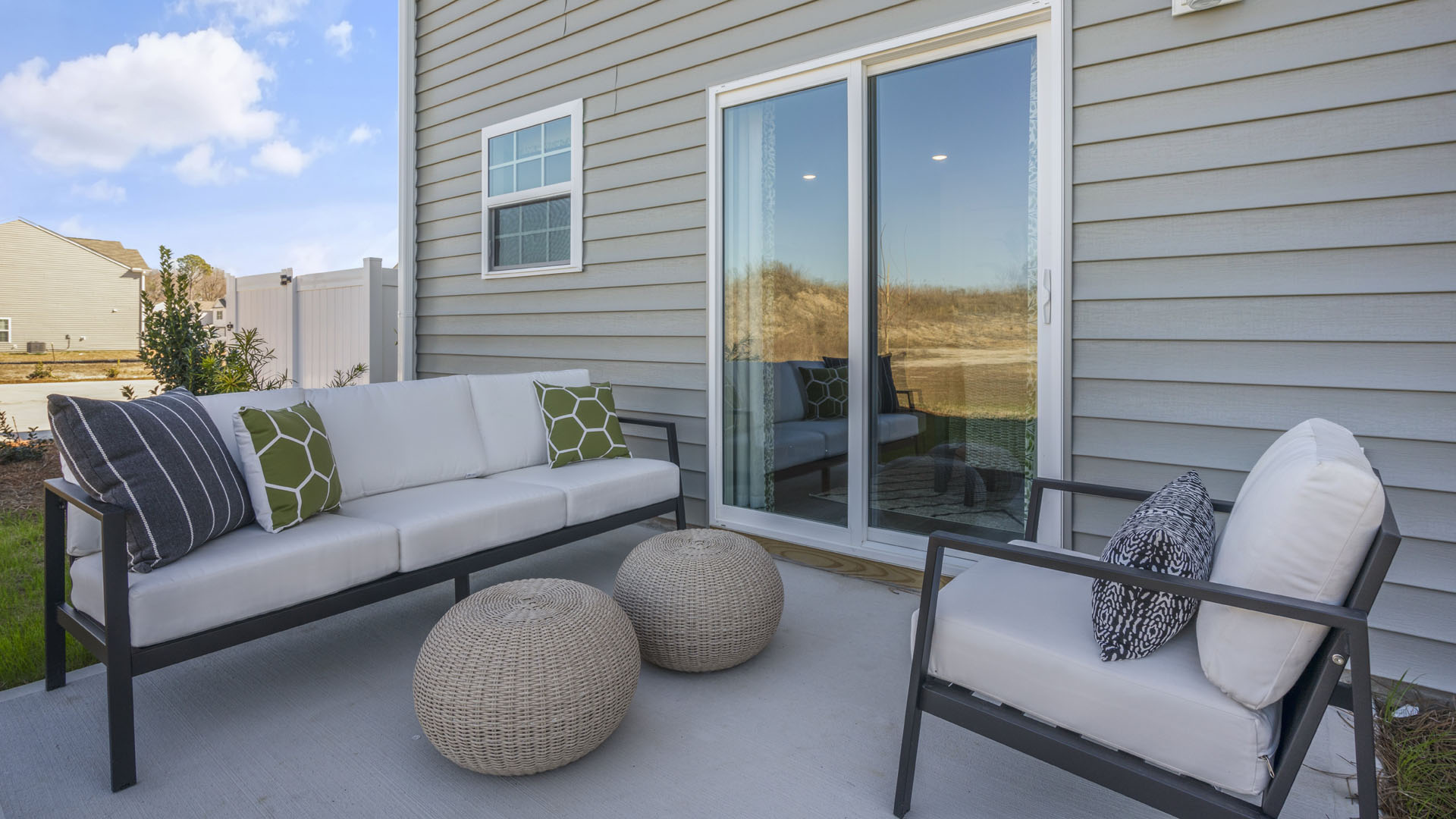 Back concrete patio with modern furniture, large sliding door, and comfy feet rests.