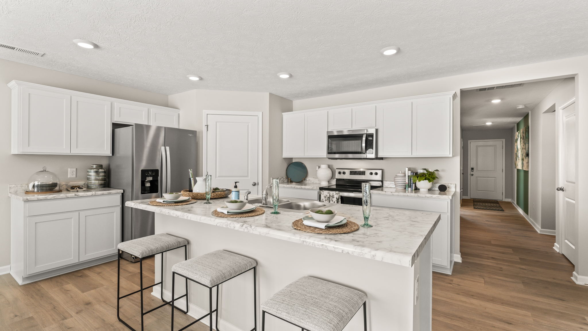 Wide angle image of modern kitchen with island, countertops, and white cabinetry