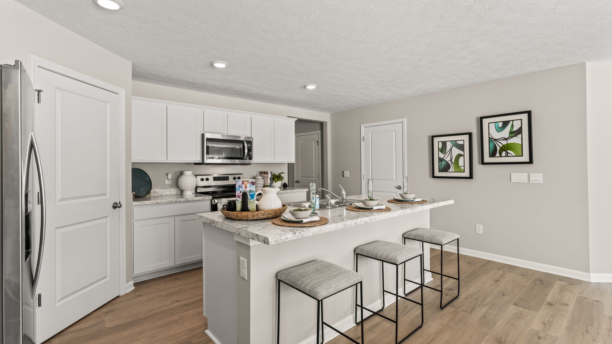 Wide angle image of modern kitchen with island, countertops, and white cabinetry