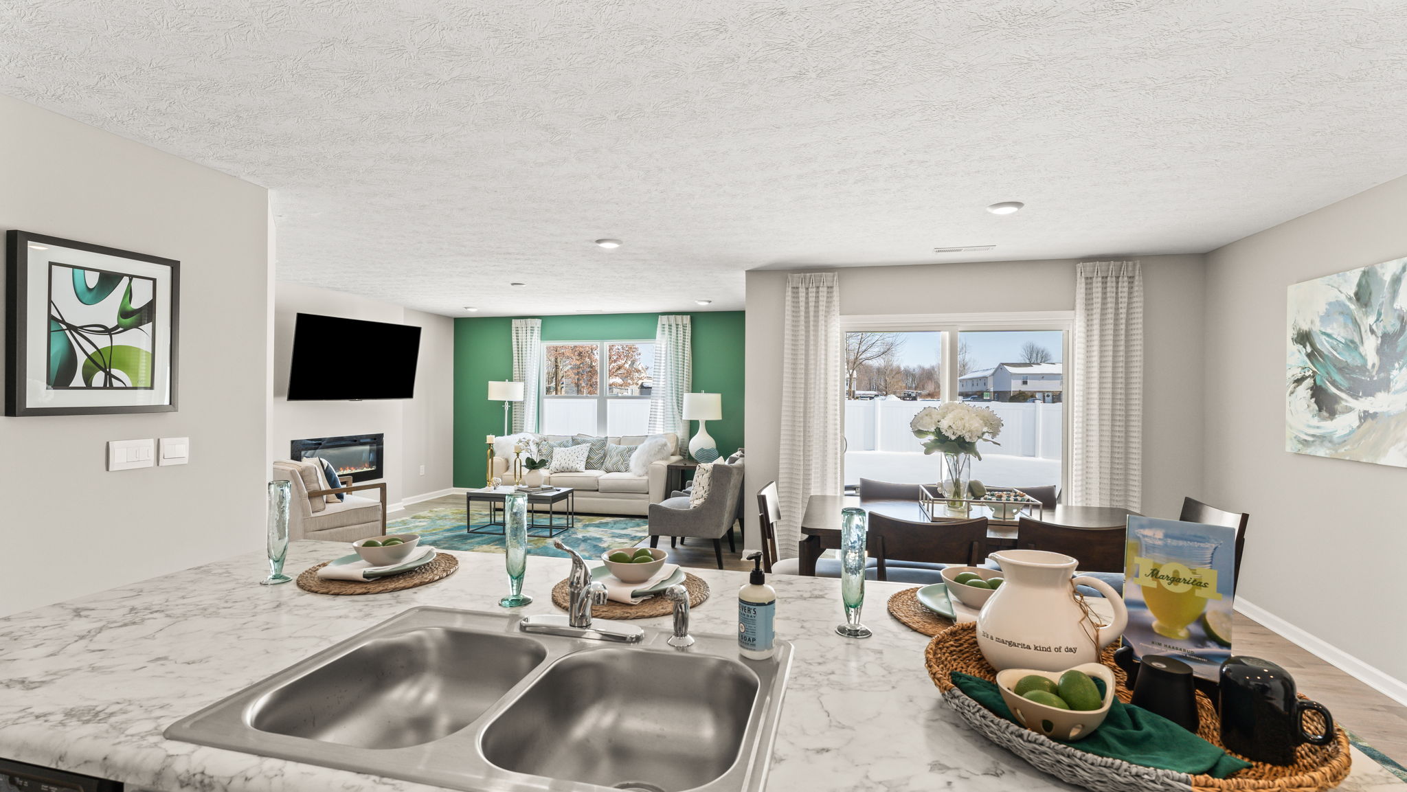 Full view of the dining and great room with green, white, and brown earthy themes