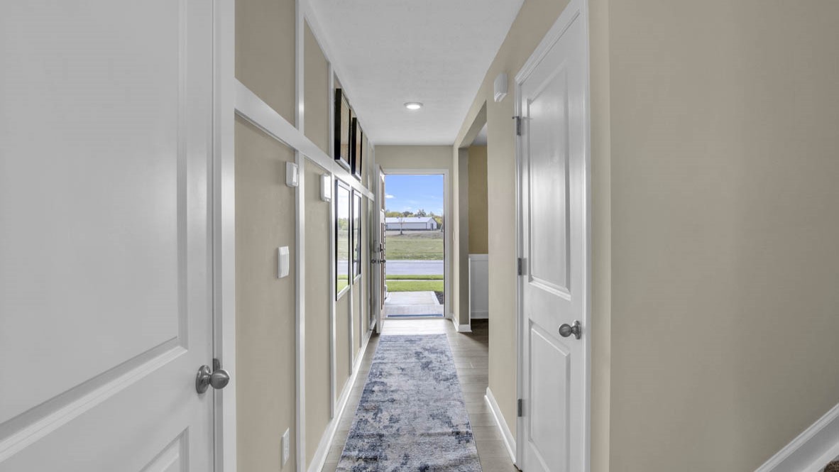 Hallway leading to the front door with white doors to storage area