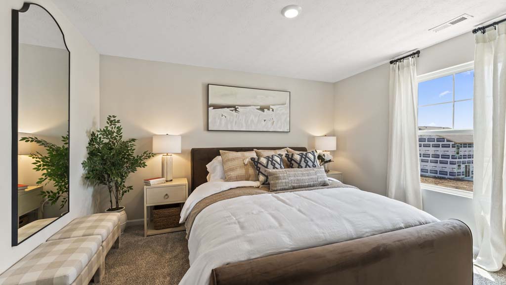 Primary bedroom with brown, tan, and beige bedding with abstract art and mirror on the walls