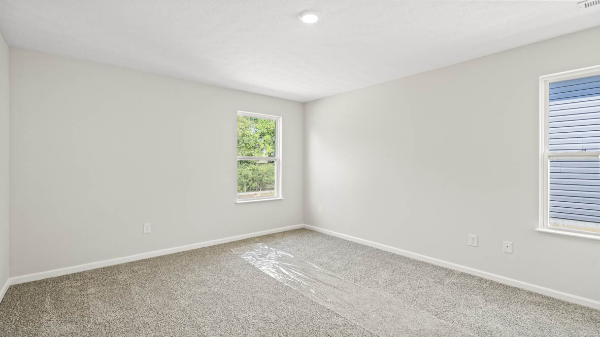Primary bedroom with two windows and carpet