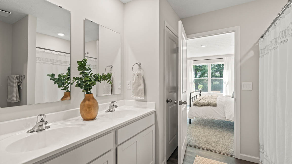 Primary Bathroom with dual vanity sinks and doorway to Primary bedroom.