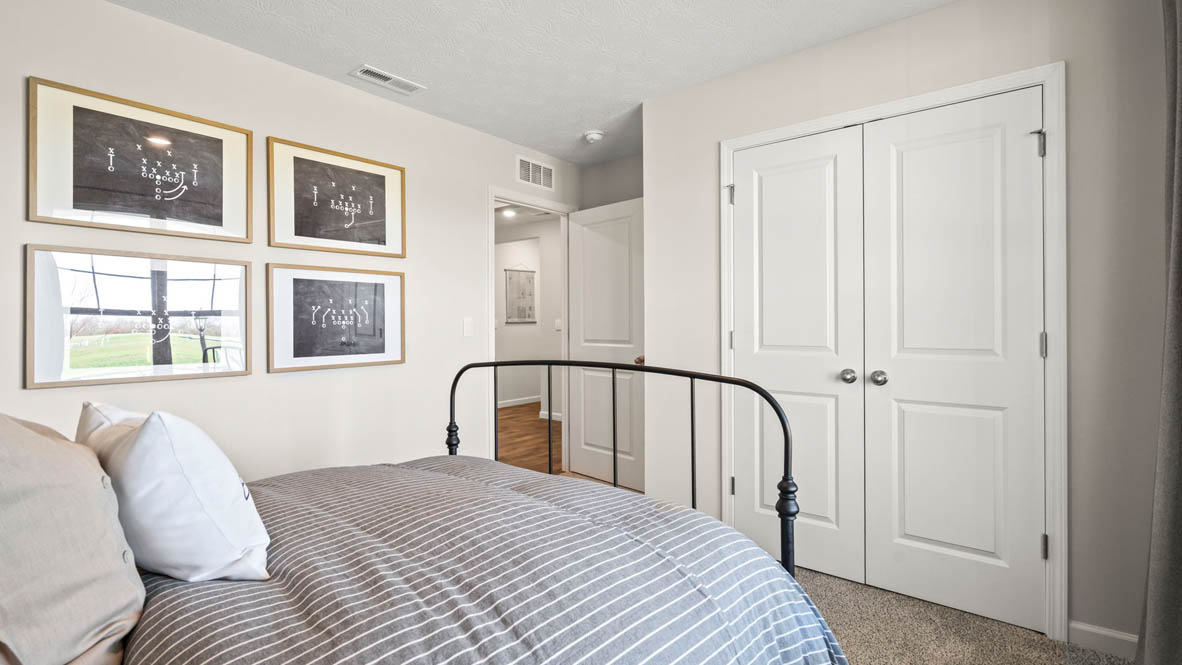 corner view of front bedroom with closet doors and football decorations.