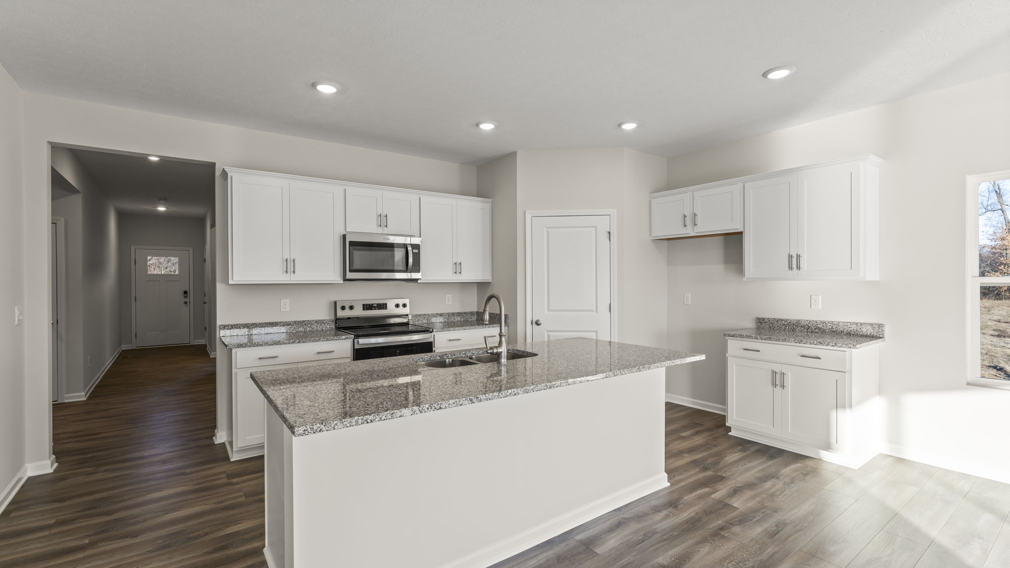 Three-quarter view of kitchen with island, white cabinetry,