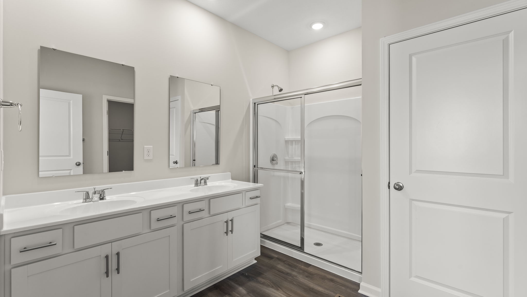 Primary bathroom with dual-vanity sink, mirror, and walk-in shower.