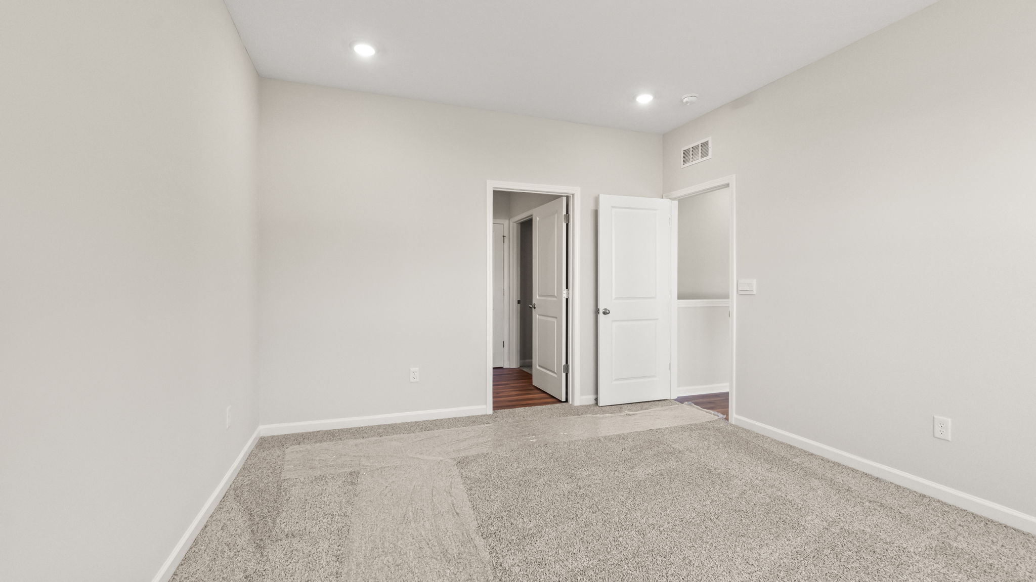 carpeted primary bedroom with view of door to bathroom suite