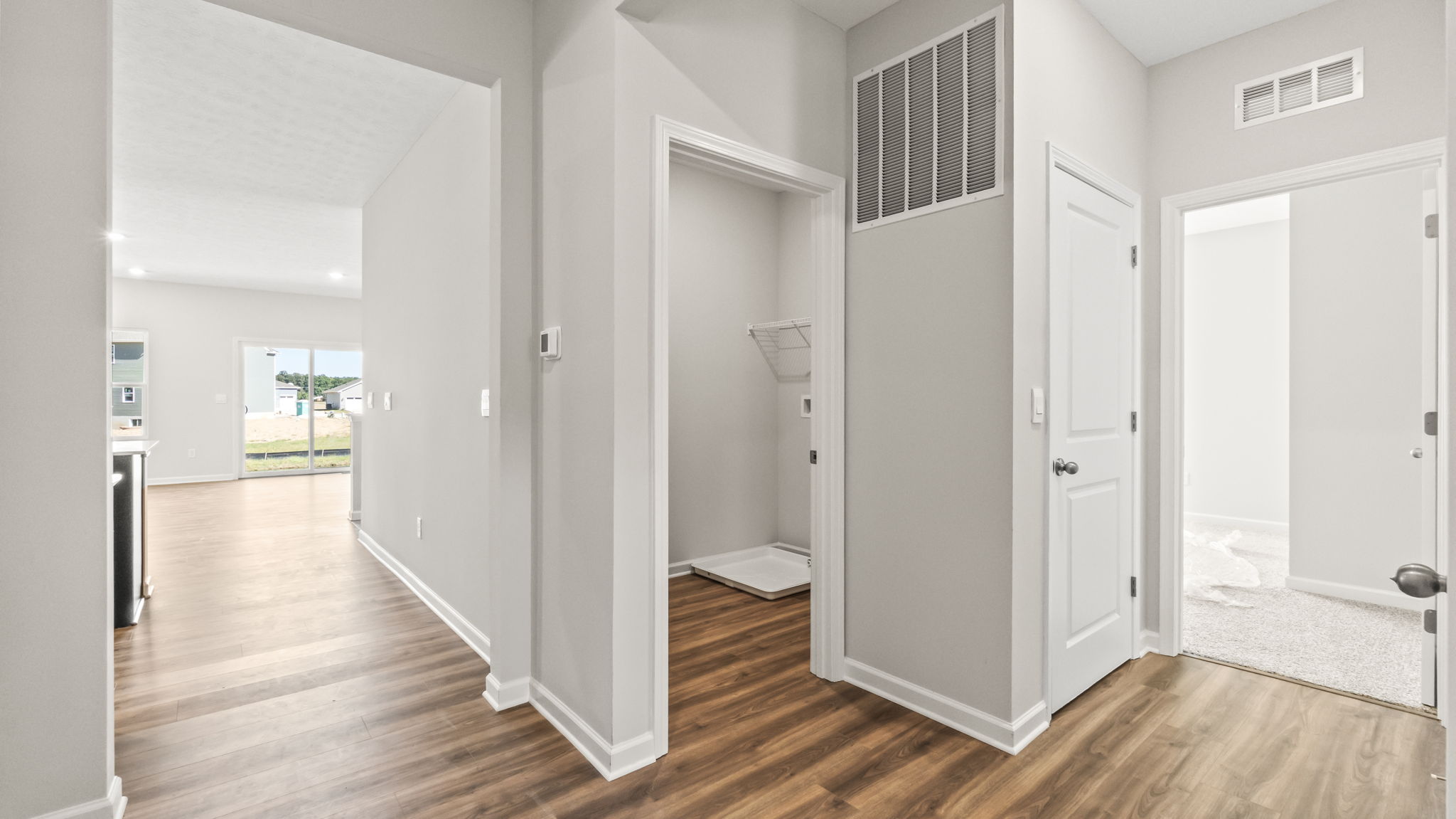 foyer leading to great room on left, laundry room in center, and bedroom on the right