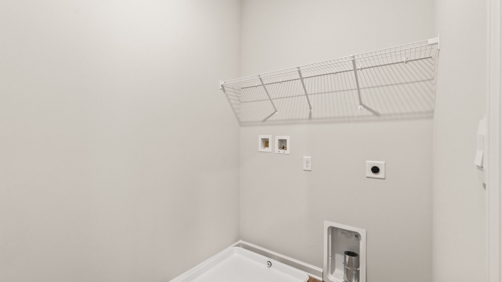 Laundry area with washer/dryer inlets and wire rack shelving