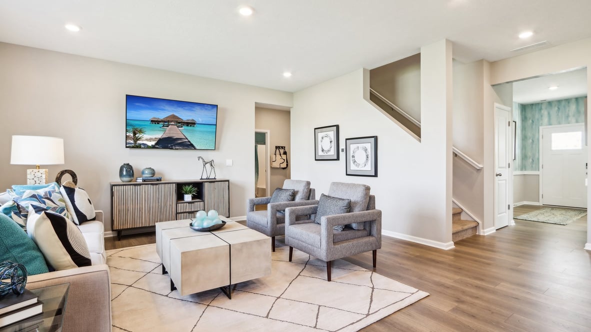Living room with brown couches, green/brown pillows, white walls, and modern coffee table