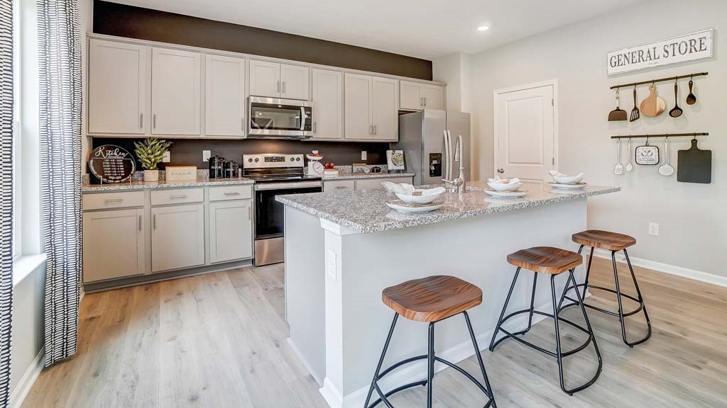 Full view of the open concept kitchen with gray cabinets and granite countertops.