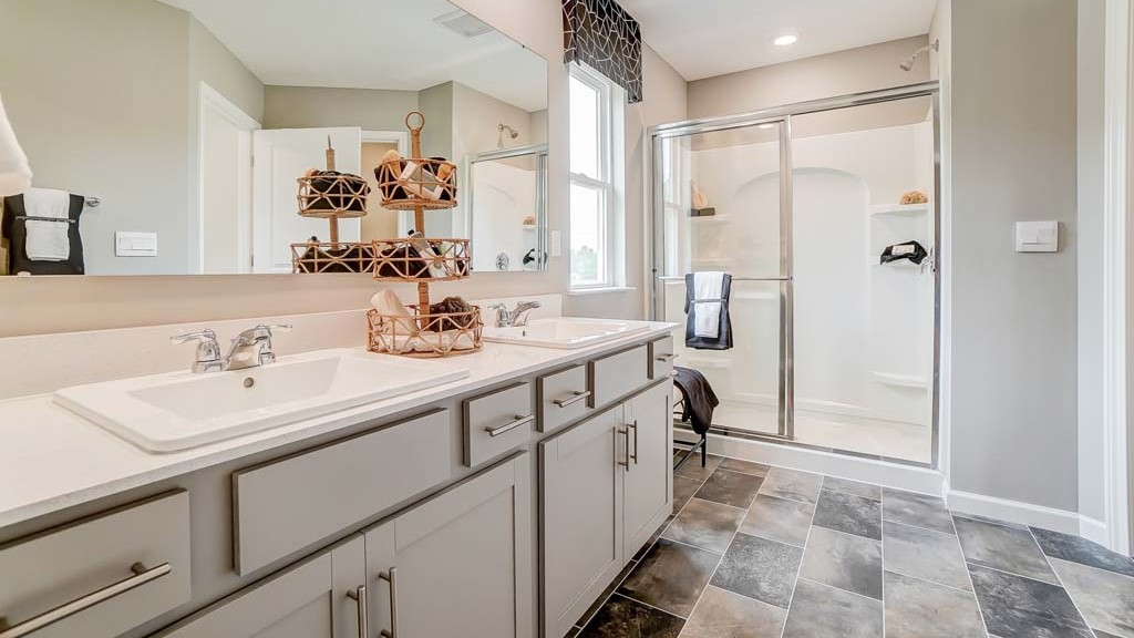 Primary bathroom with dual vanity sinks, large mirror, and view of shower.