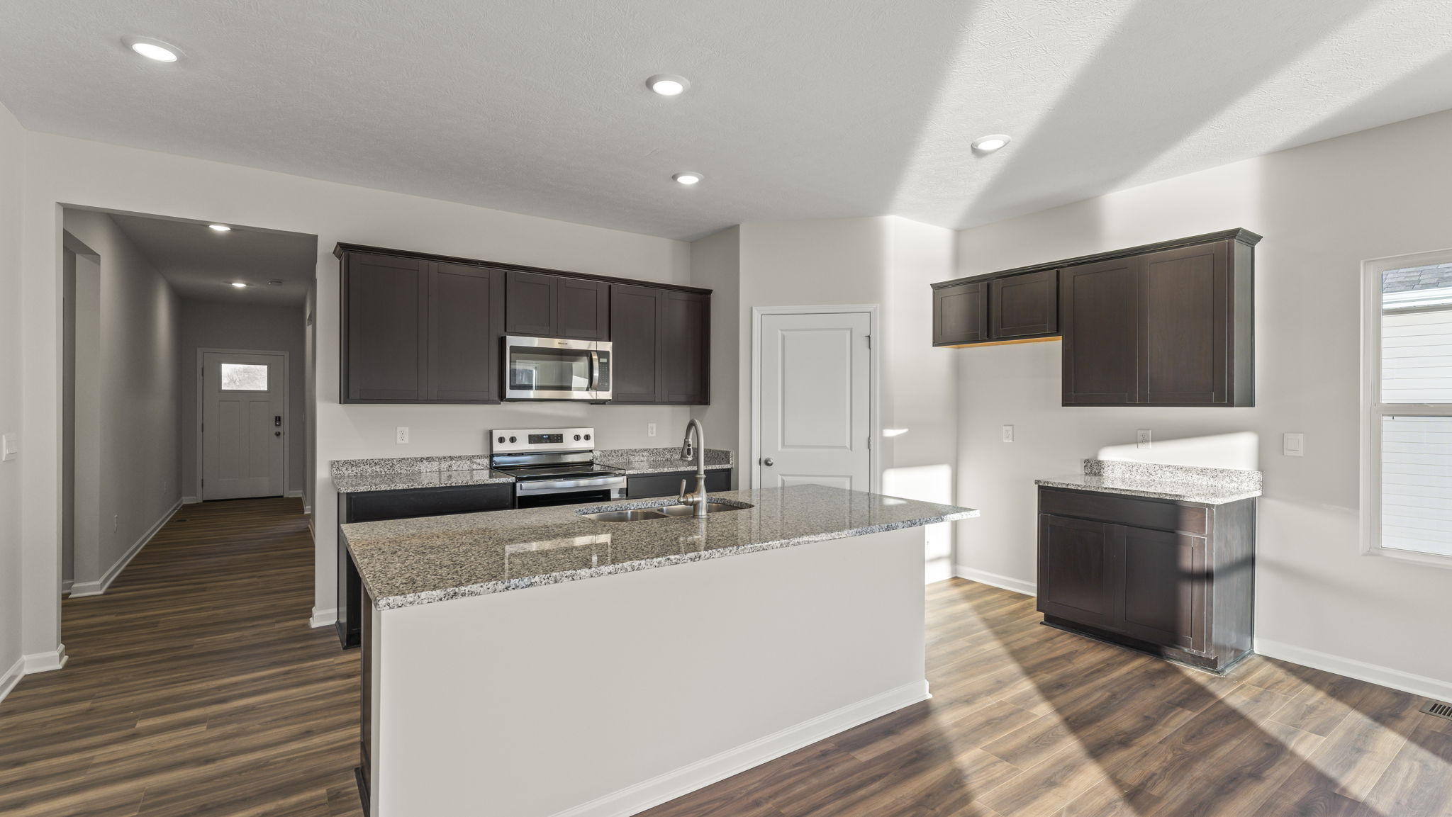 Three-quarter view of kitchen with granite countertops and brown cabinetry
