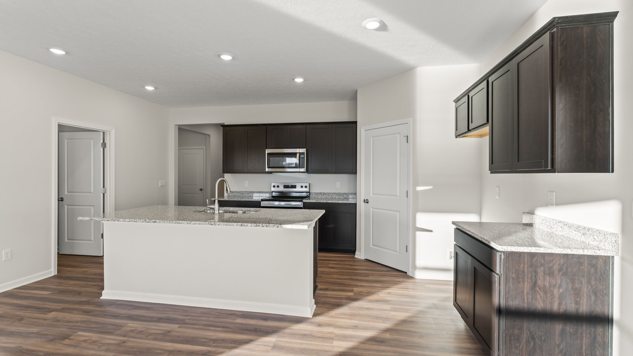 Three-quarter view of kitchen with granite countertops and brown cabinetry