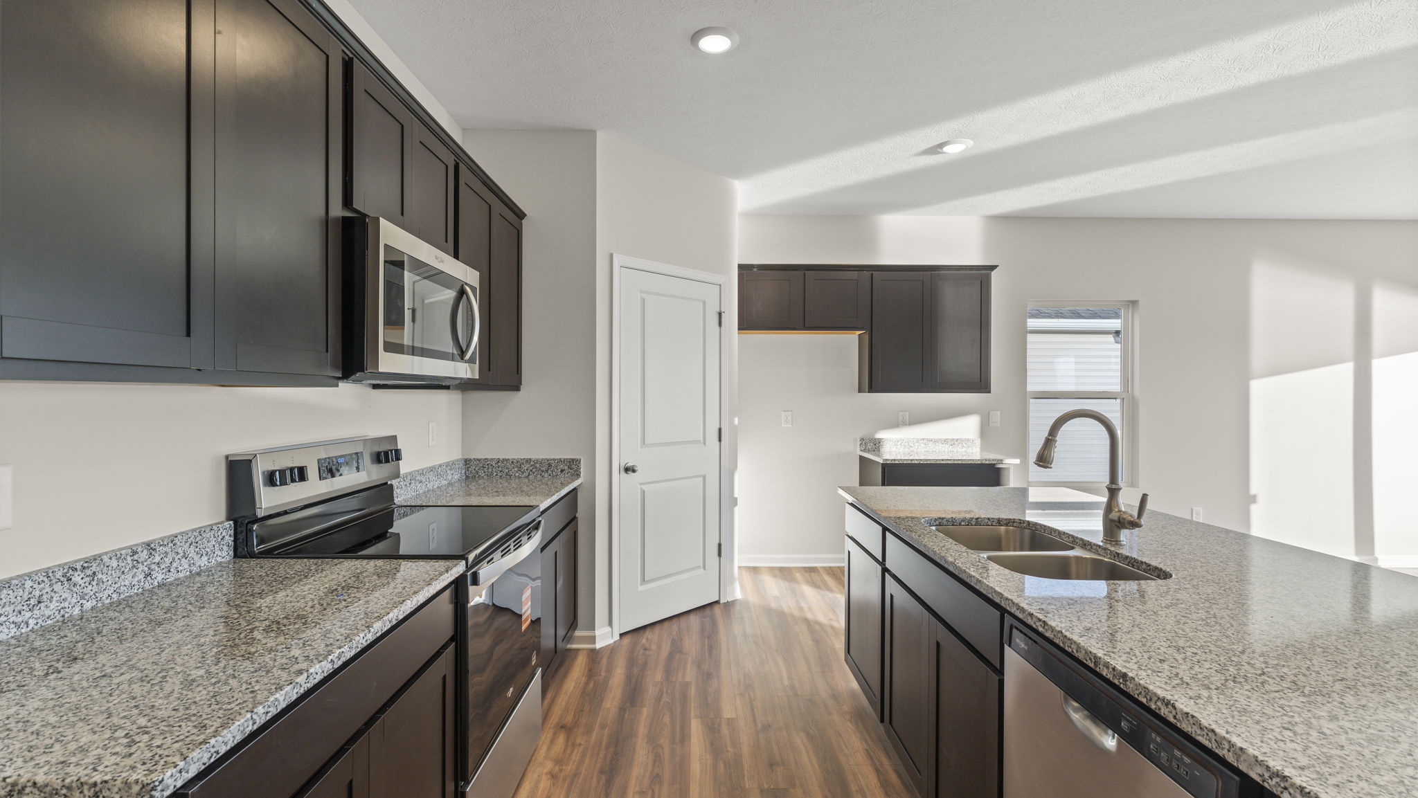 side view of kitchen with island on the right, pantry in the center, and oven range on the left