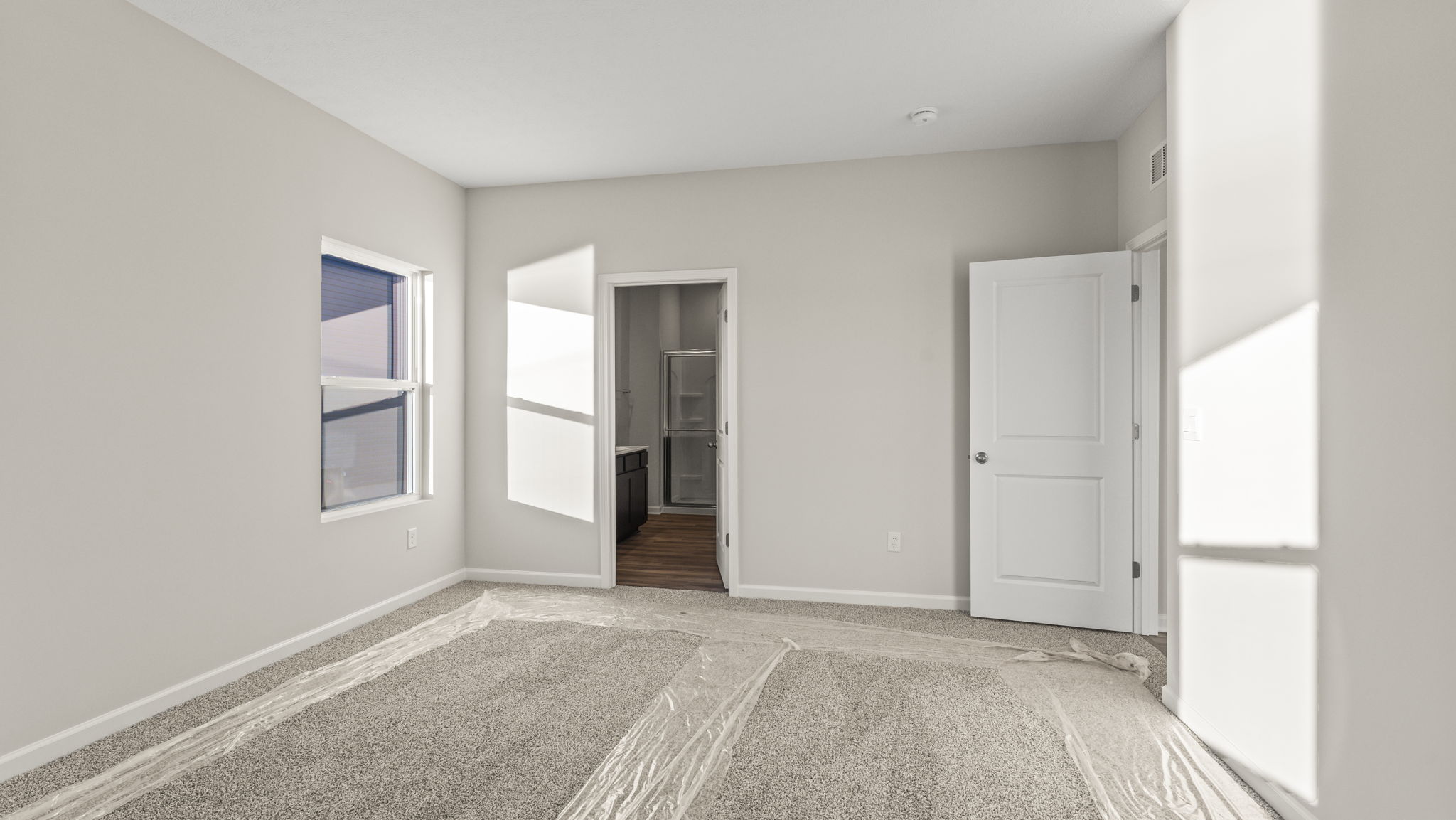 Carpeted primary bedroom with bathroom in the back