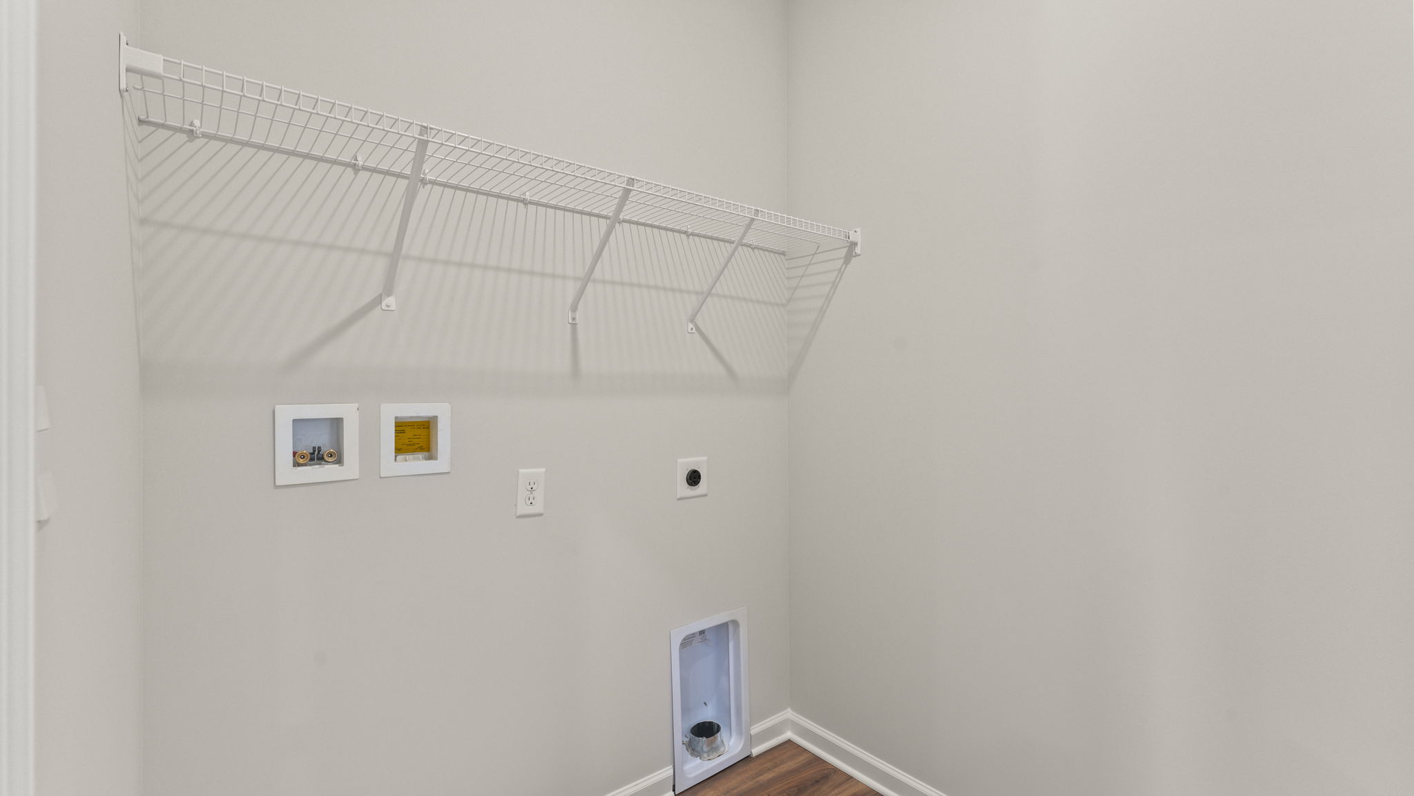 Laundry area with washer/dryer inlets and wire rack shelving.
