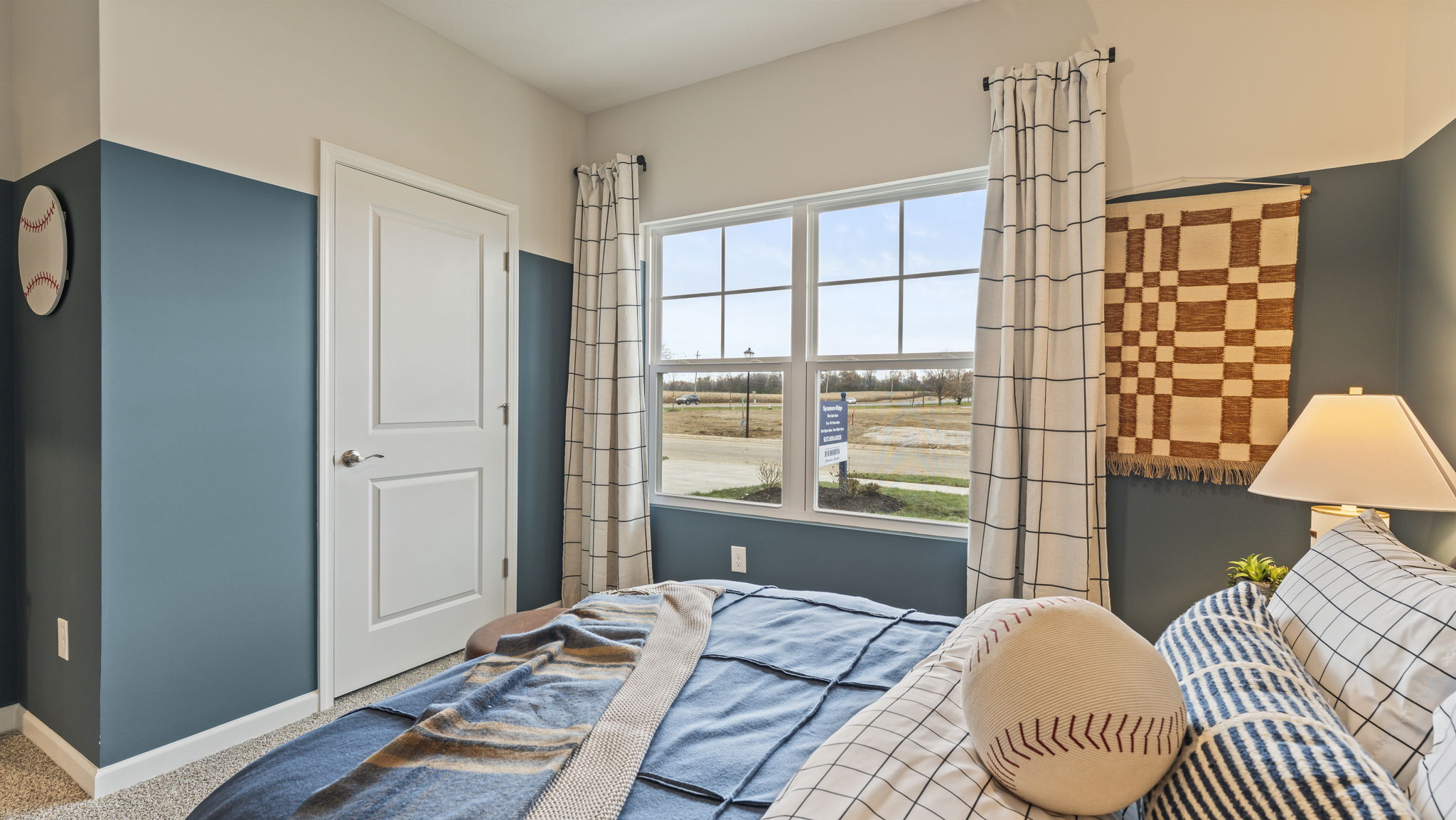 Side view of bedroom with checkered tapestry on wall, window to outside, and closet door for storage.