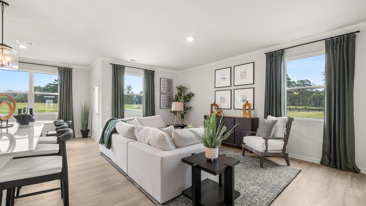 Full great room with white, green, and brown furniture, plants, and contemporary art on walls