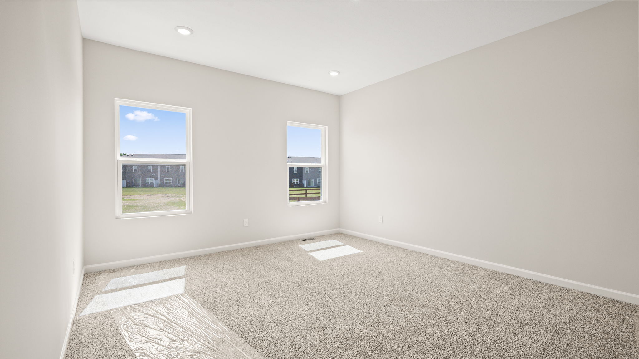 Carpeted primary bedroom with two windows