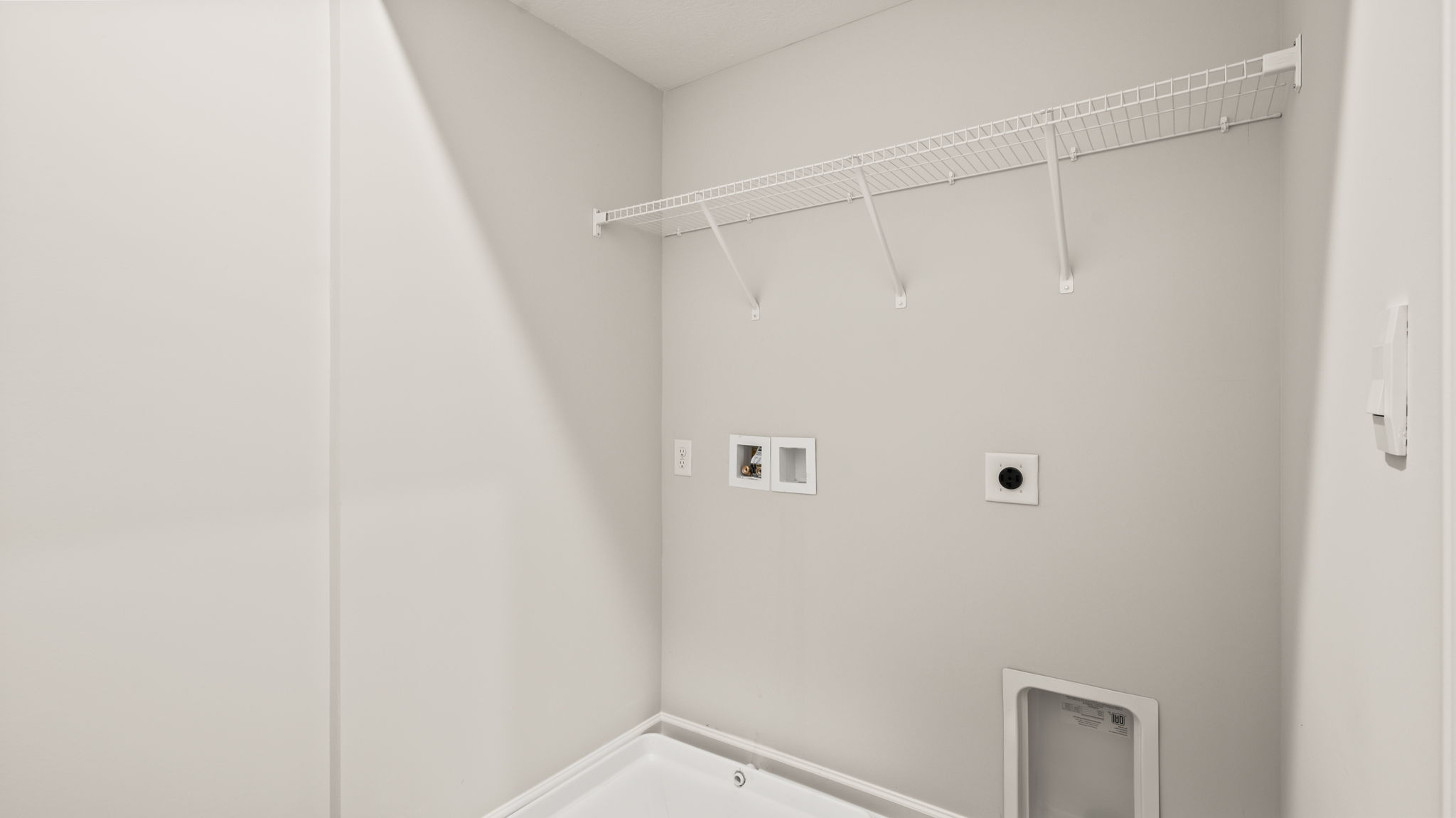 Laundry area with wire rack shelving and washer/dryer inlets