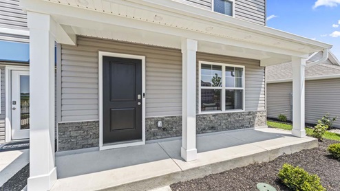 Covered front patio of home with a large window.