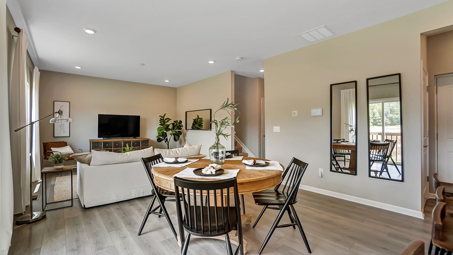 Wooden dining table with black chairs and living room.