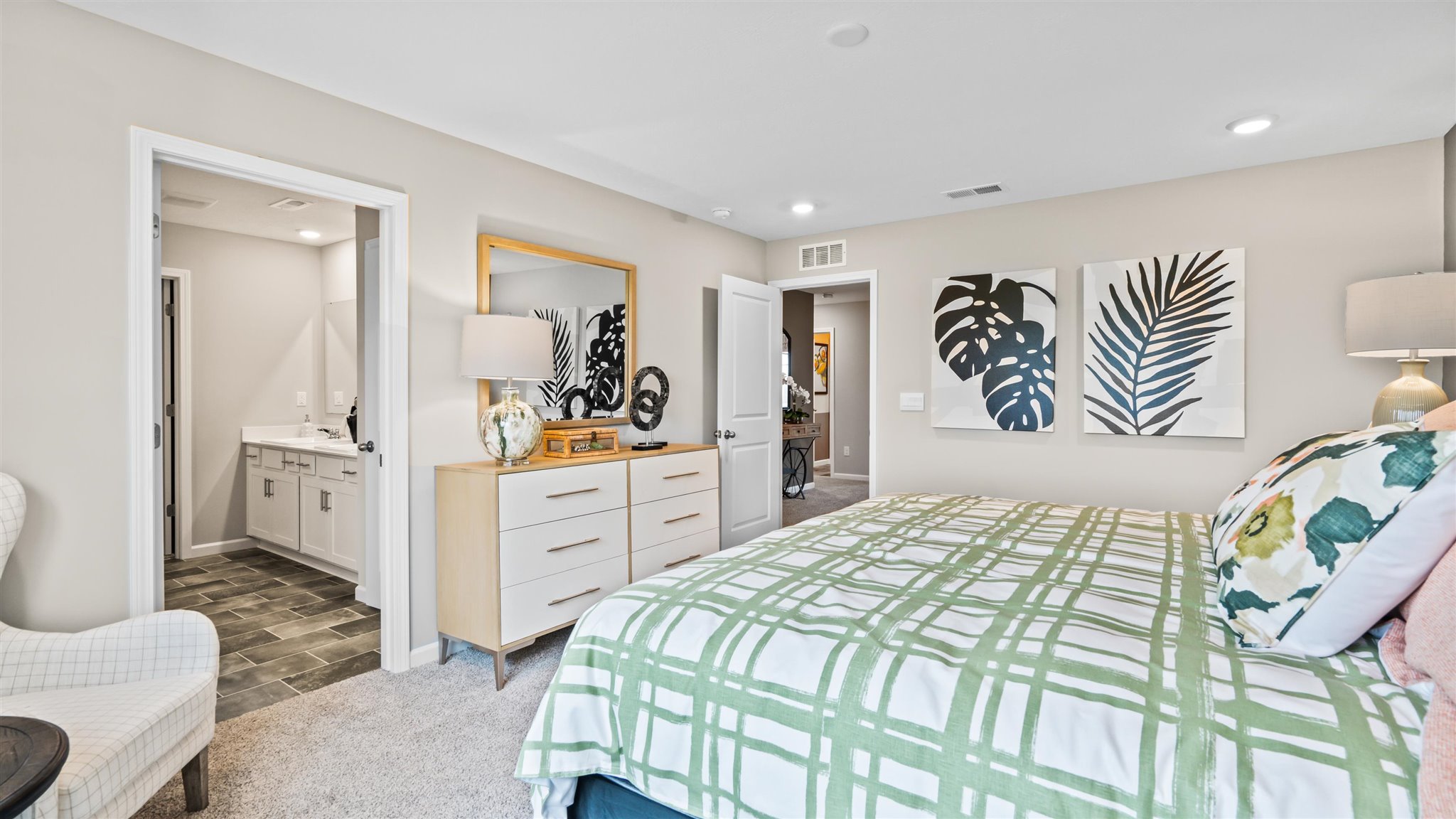 Primary bedroom with large king bed, modern art, and view into the private bathroom.