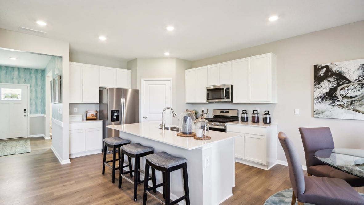 Full kitchen with island, white cabinetry, and appliances.