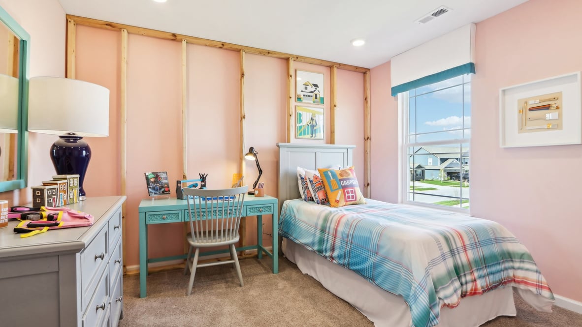 Pink and light blue bedroom with desk and frame decoration.